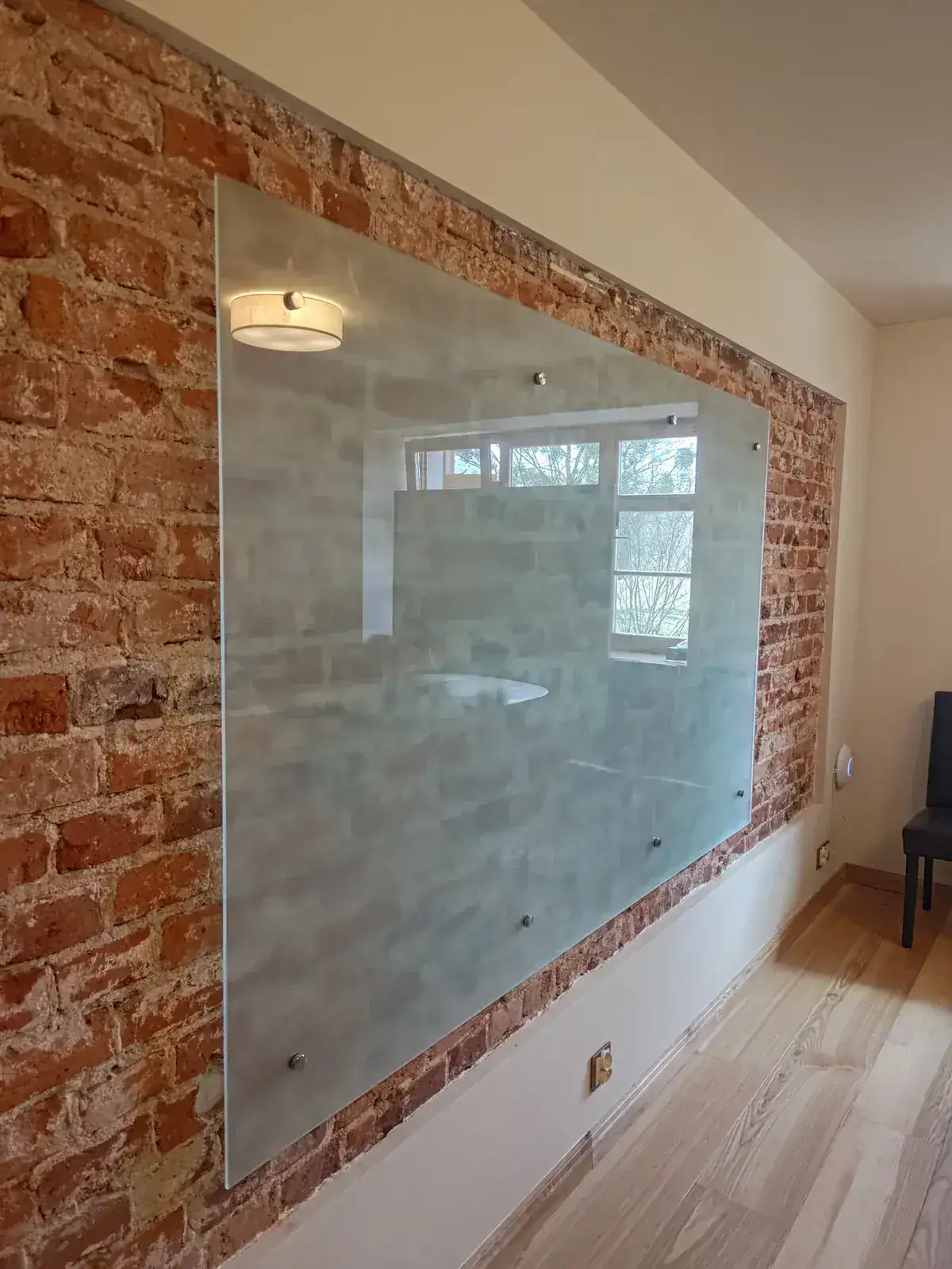 tablica szklana zamontowana na dystansach na ścianie z cegły – zbliżenie