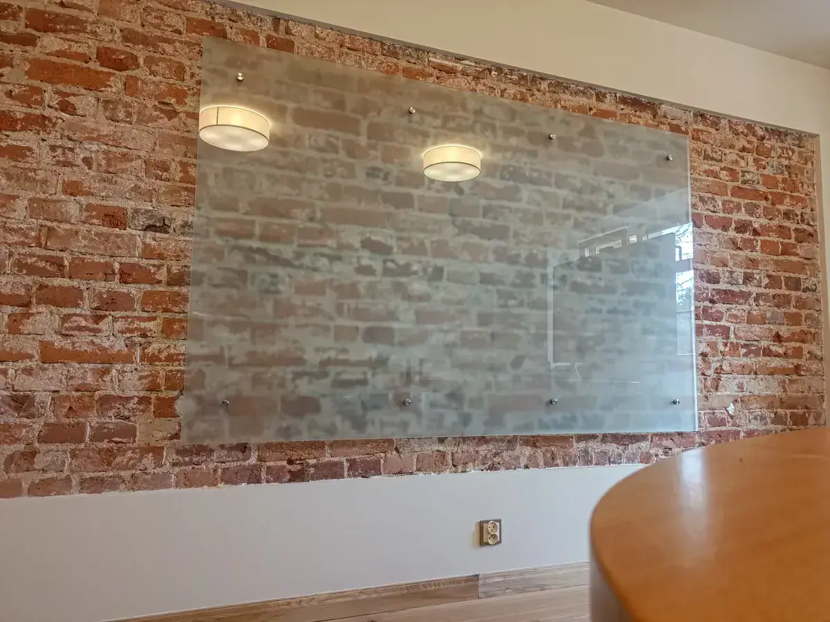 tablica szklana na wymiar na ścianie z cegły – widok z boku